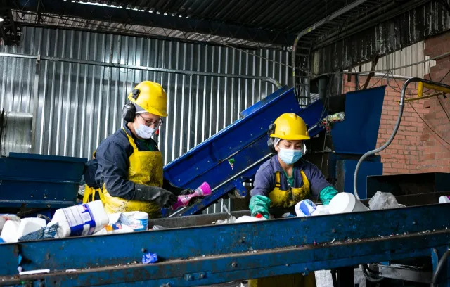 Representación de dos trabajadoras reciclando en una fábrica 