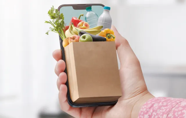 mano con celular y bolsas de comprar
