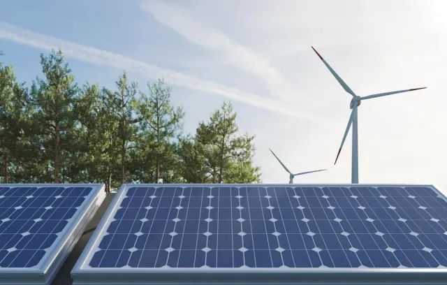 Foto de un panel solar y de fondo una de energía aeólica