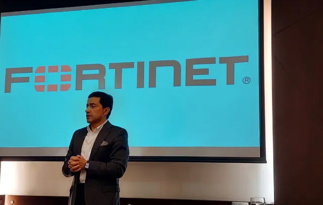 foto de un hombre exponiendo un tema frente a una pantalla que dice Fortinet