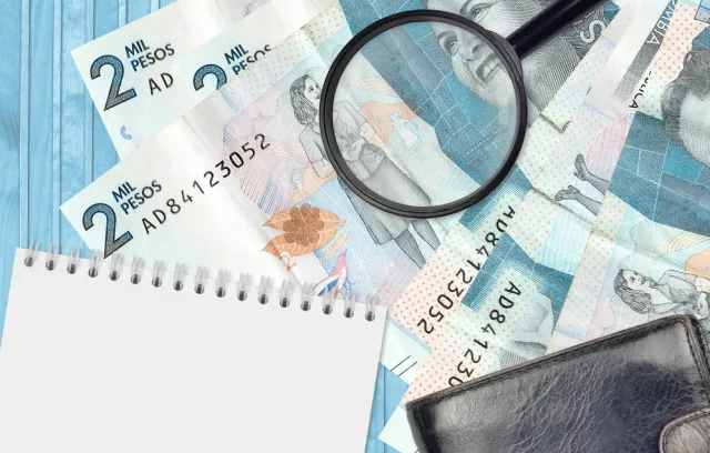 Foto de billetes sobre una mesa con una lupa encima