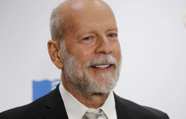 Foto de bruce willis, un señor con barba en traje y fondo blanco