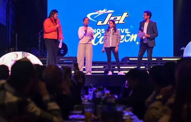 Foto de cuatro personas en un escenario con la marca jet de fondo