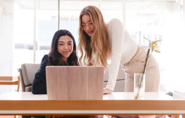 Foto de dos mujeres hablando con una computadora al frente