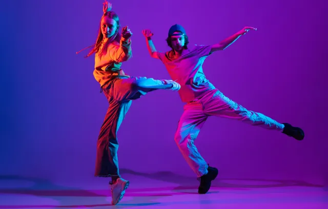 Foto de dos personas bailando con un fondo morado 