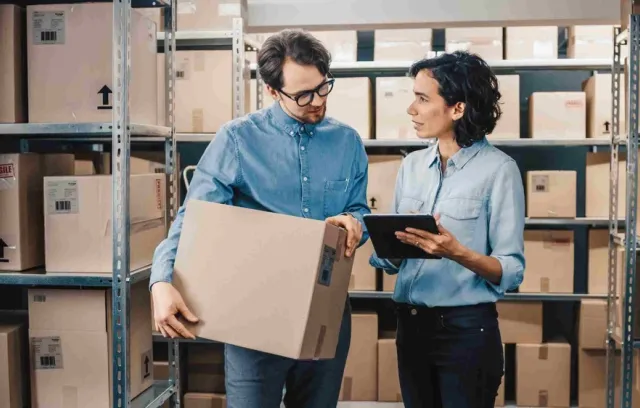 Foto de dos personas hablando con cajas de fondo