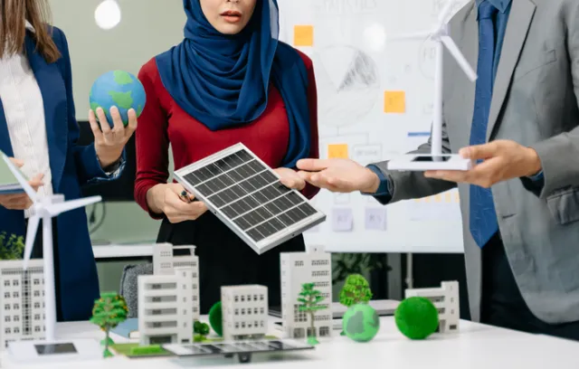 Foto de ejecutivos mirando un panel solar con un proyecto en la mesa