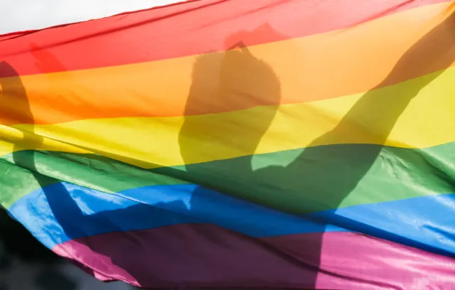 Foto de la silueta de un hombre detrás de una bandera inclusiva