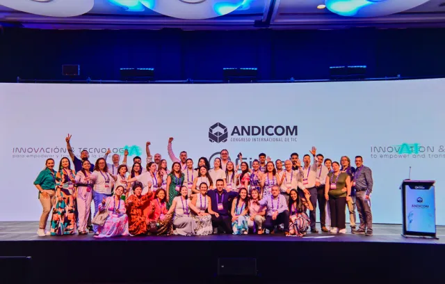 Foto de más de 10 personas reunidas frente a la cámara y un fondo de Andicom en el fondo