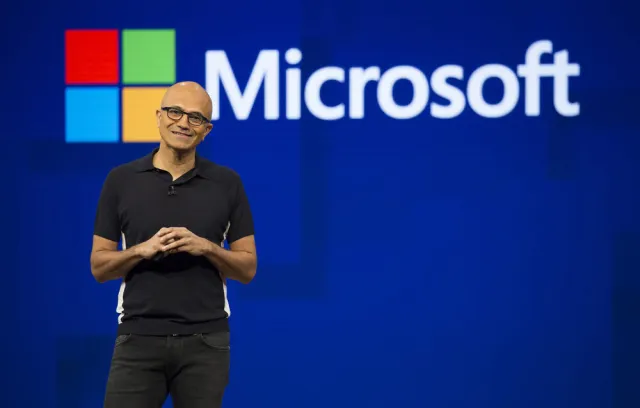 Foto de un señor explicando un tema frente  un fondo de Microsoft