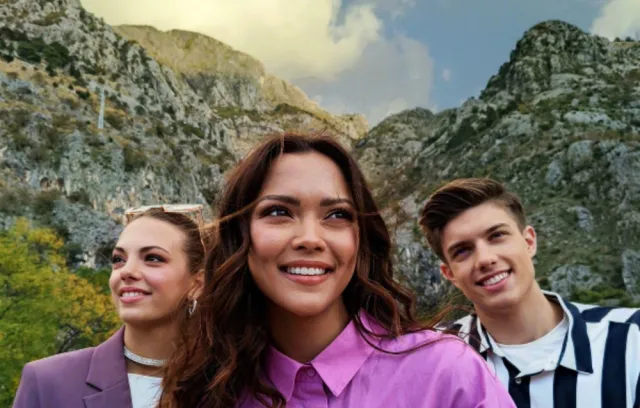 Foto de tres personas mirando a la cámara con una montaña de espaldas