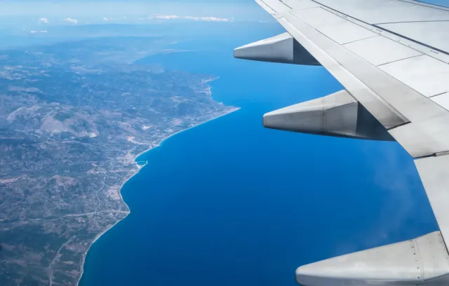 Foto de un ala de un avión y debajo la tierra y el mar