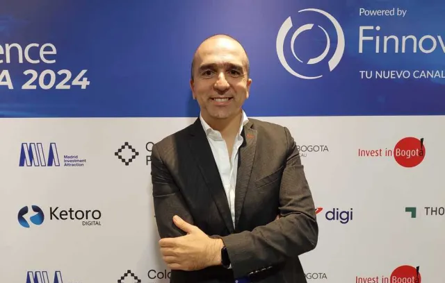 Foto de un ejecutivo mirando a la cámara con un fondo d eun evento promocional