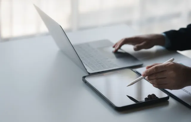 Foto de un empresario con un computador en un lado de la mesa y una tablet en el otro