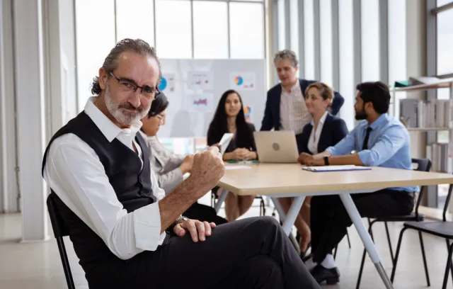 Foto de un empresario mirando a la cámara con personal detras