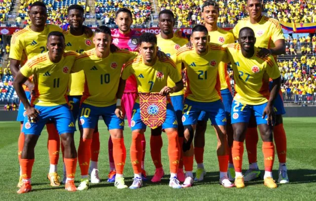 Foto de un equipo de fútbol tomados de los brazos con un fondo muticolor