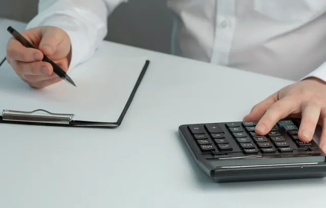 Foto de un hombre con una calculadora y una hoja de papel