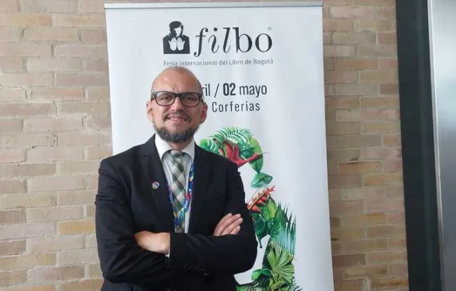 Foto de un hombre cruzado de brasil con barba y gafas negras mirando a la cámara