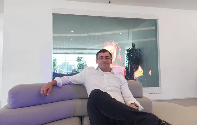 Foto de un hombre sentado sobre un sofa mirando la cámara con la pierna cruzada