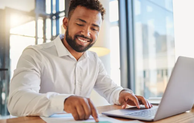 Foto de un hombre sonriendo mientras tiene una comutadora al frente