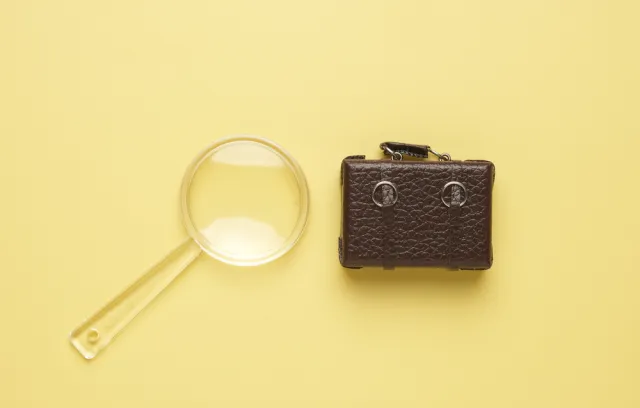 Foto de un maletin y una lupa pequeña con un fondo amarillo