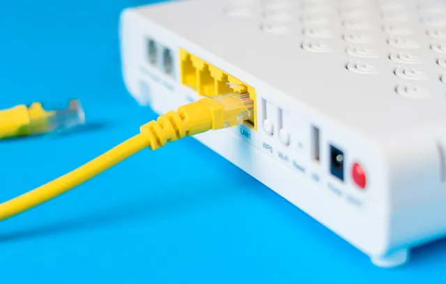 Foto de un modem blanco con cableado amarillo y fondo azul