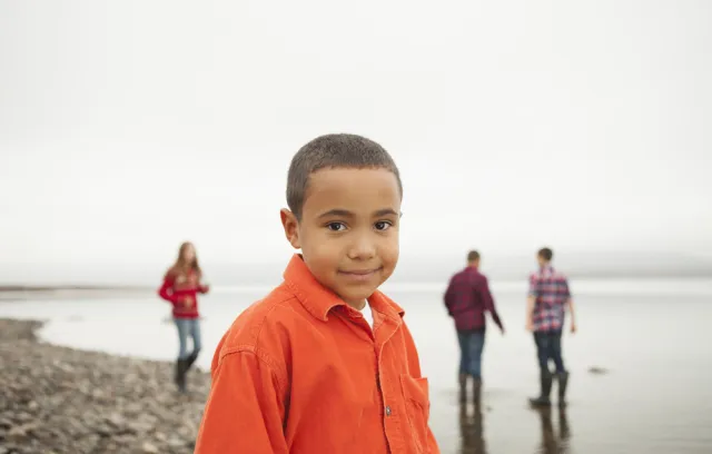 Foto de un niño  con camiseta naranja mirando a la cámara 