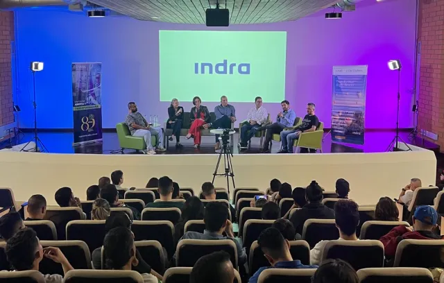 Foto de un panel con varias personas sentadas conversando frente a un auditorio