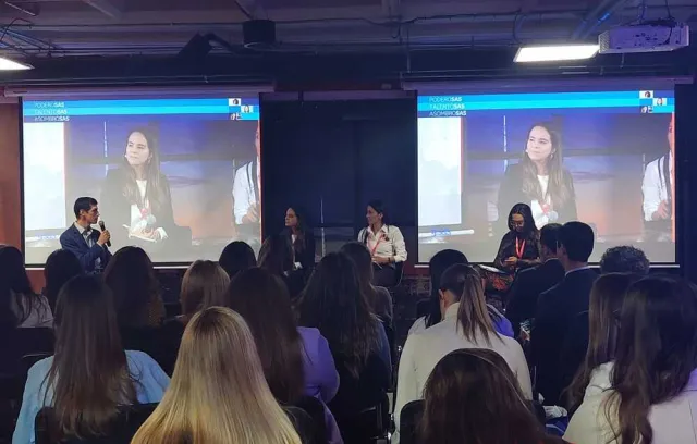 Foto de un salón lleno de personas con mujeres panelistas