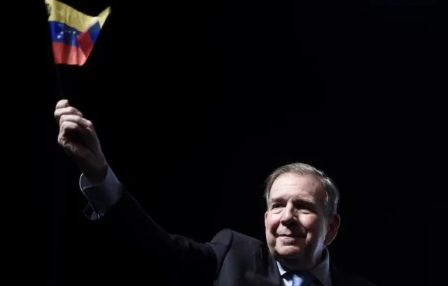 Foto de un señor con la bandera de venezuela en la mano derecha
