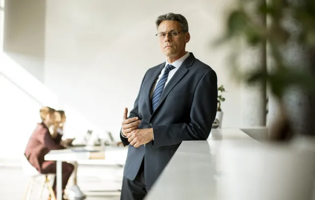 Foto de un señor mirando a la cámara con un equipo de fondo