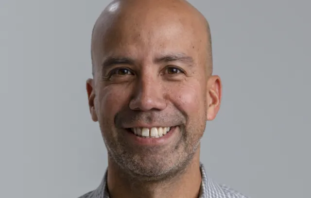 Foto de un hombre sonriente con un fondo gris