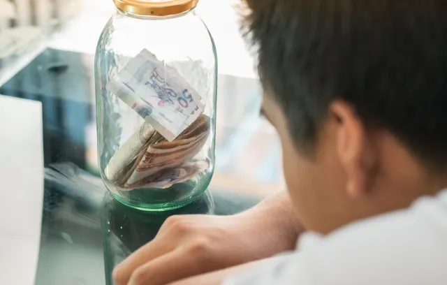 Foto de un señor mirando un frasco con dinero colombiano