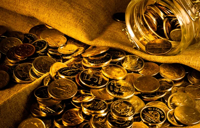 Foto de varias monedas de oro sobre una bolsa de oro