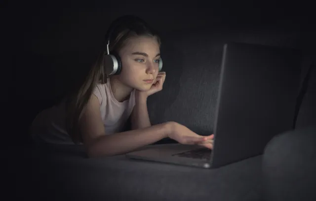 Foto de una chica mirando la computadora en la noche