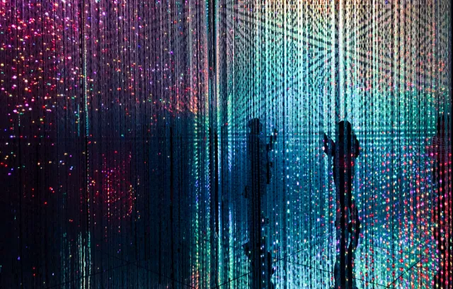 Foto de una exhibición de arte con varias luces y dos siluetas de fondo