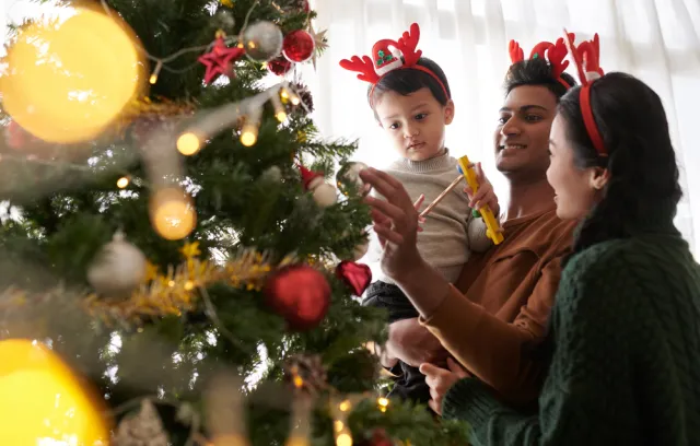 Foto de una familia poniendo objetos en un árbol de navidad