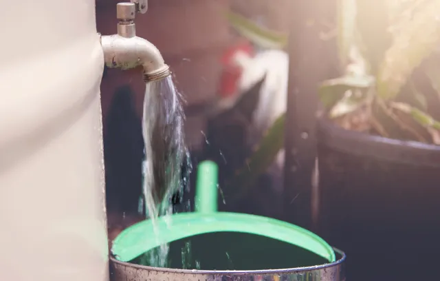 Foto de una llave de agua distribuyendo agua a un balde