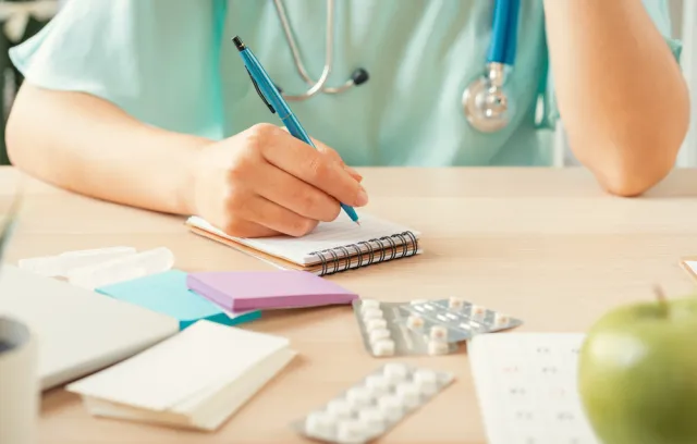 Foto de una médica escribiendo sobre una hoja de papel
