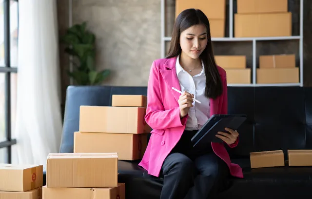 Foto de una mujer con blazer rosado con cajas al fondo