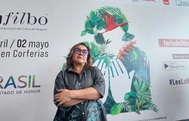 Foto de una mujer con gafas  rofas mirando a la cámara, plano americano