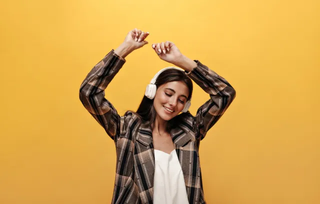 Foto de una mujer escuchando música con un fondo amarillo