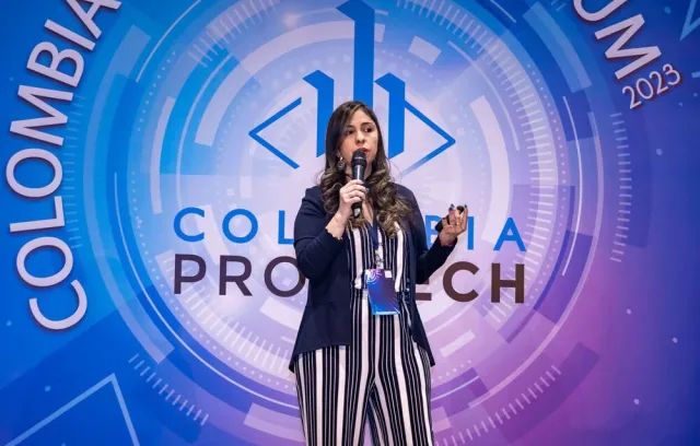 Foto de una mujer exponiendo frente a un logo azul Colombia protech 2024