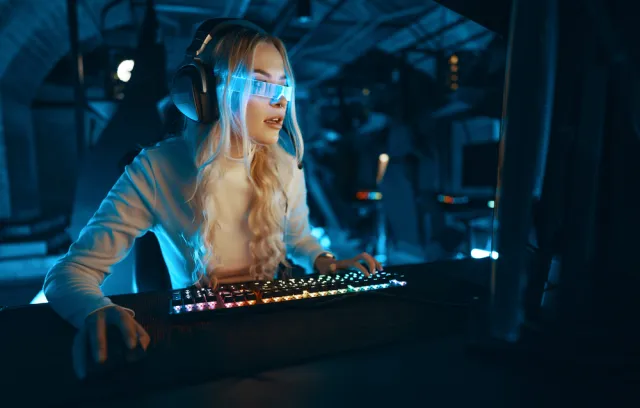 Foto de una mujer mirando un computador con unas gafas azules