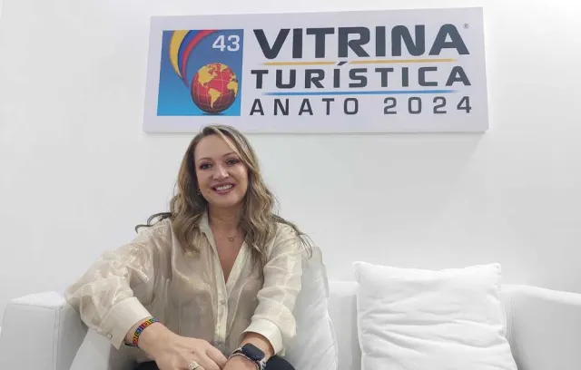 Foto de una mujer sentada en un colchón con fondo blanco mirando a la cámara