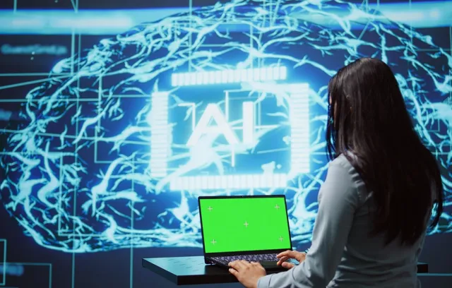Foto de una mujer sentada frente a una pantalla que dice IA. Foto de Schneider Electric