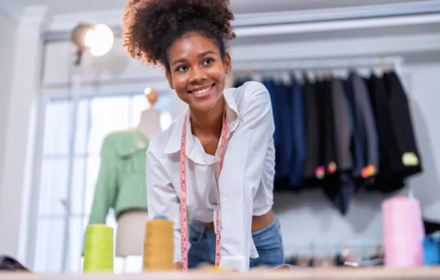 Foto de una mujer sonriendo a la cámara y de fondo unos vestidos
