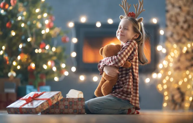 Foto de una niña con un regalo de navidad en sus brazos
