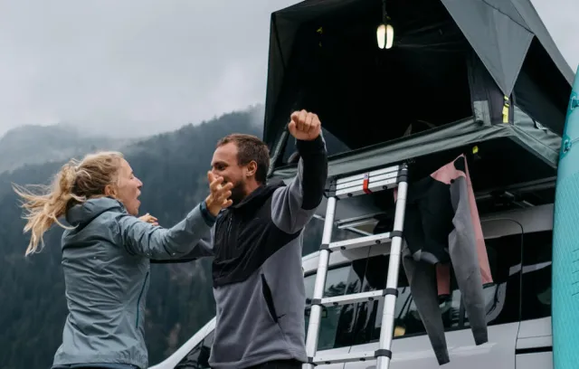Foto de una pareja acampando con una carpa plegable de fondo