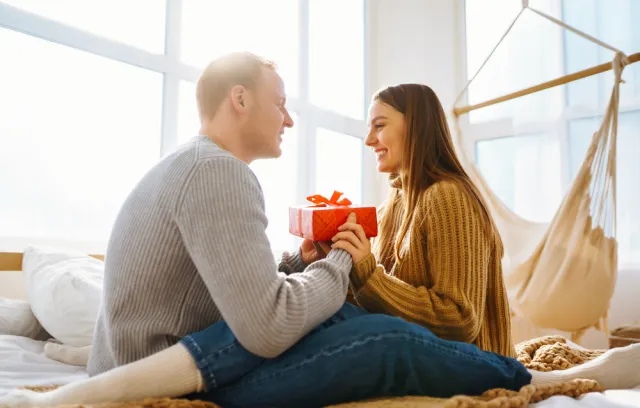 Foto de una pareja mirandose a los ojos con un regalo en sus mano